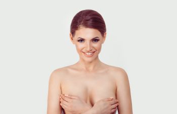 Beautiful smiling woman covering her breasts with her hands.